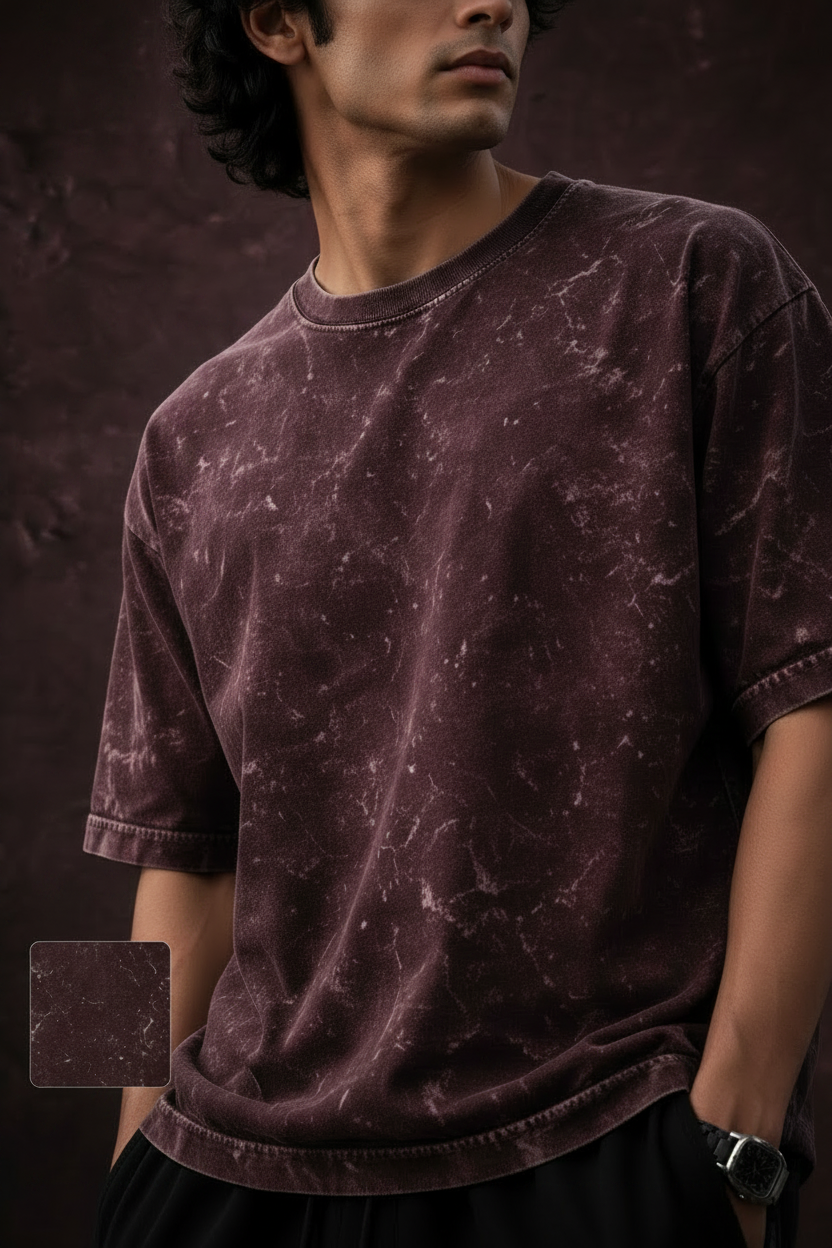 A man wearing a maroon acid-wash t-shirt with white distressed patterns, featuring promotional text and a color swatch on a dark textured background.